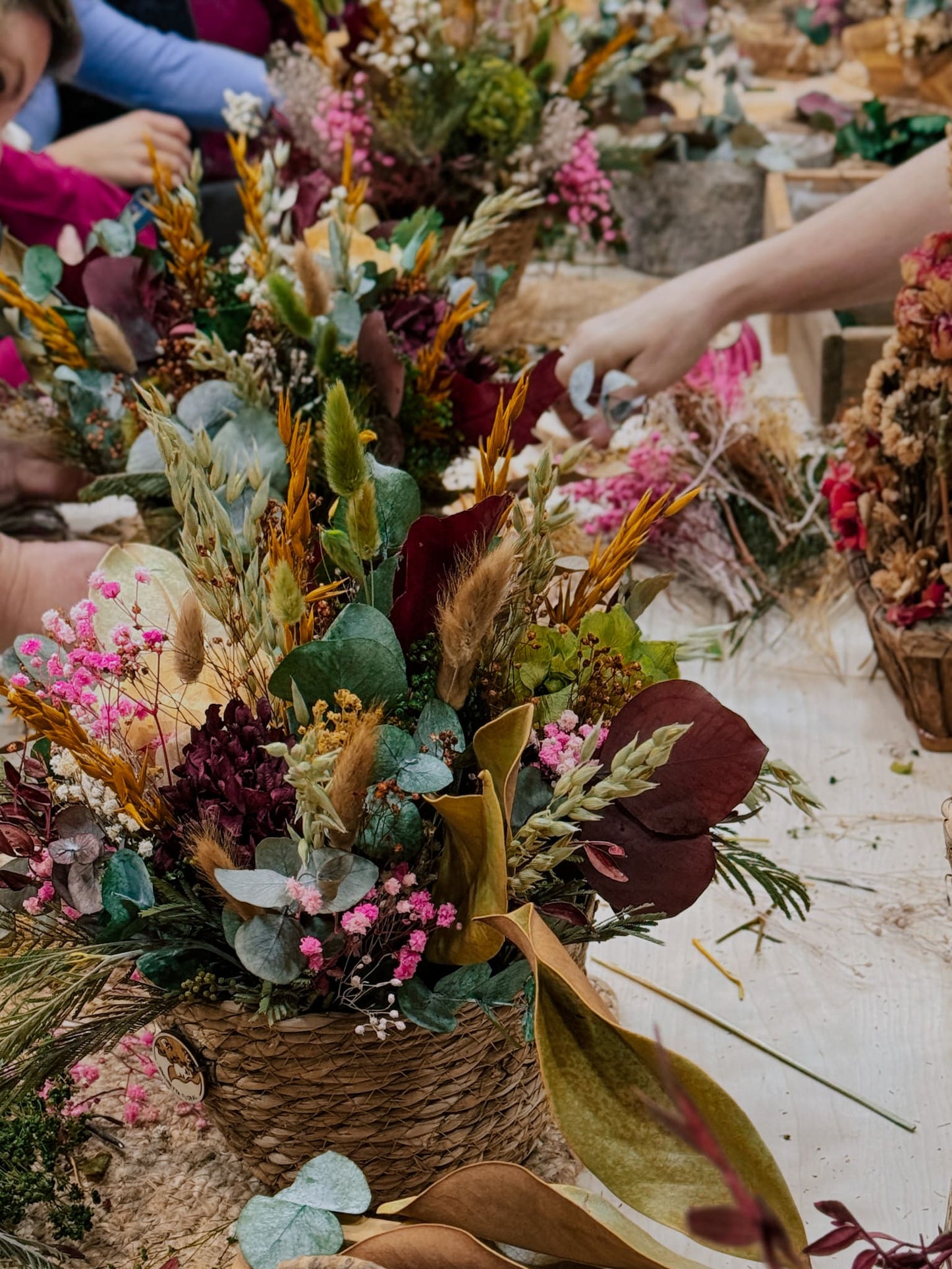 Mesa del taller floral con varios centros de flores preservadas