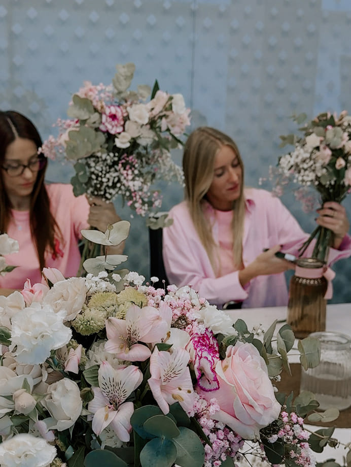 Participantes trabajando con flores frescas y composiciones florales en un taller
