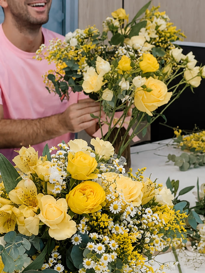 Participante creando un ramo de flores frescas en tonos amarillos y blancos