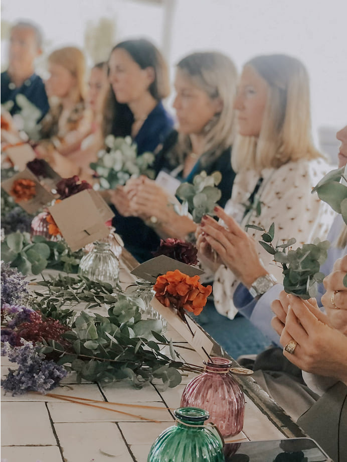 Participantes trabajando con flores preservadas durante un taller para empresas