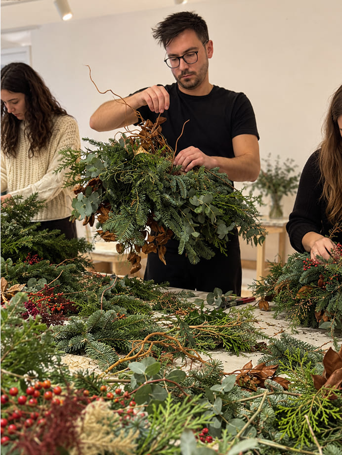 Participantes creando coronas navideñas durante un workshop floral para empresas