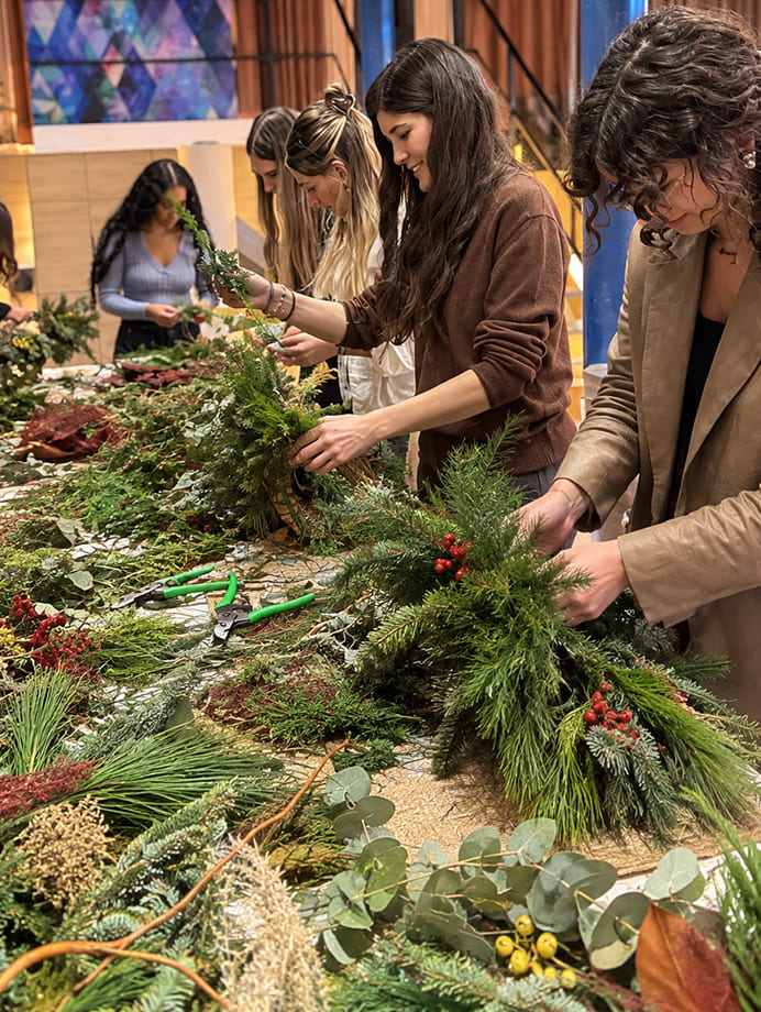 Workshop de coronas de Navidad con participantes trabajando con flores y verdes