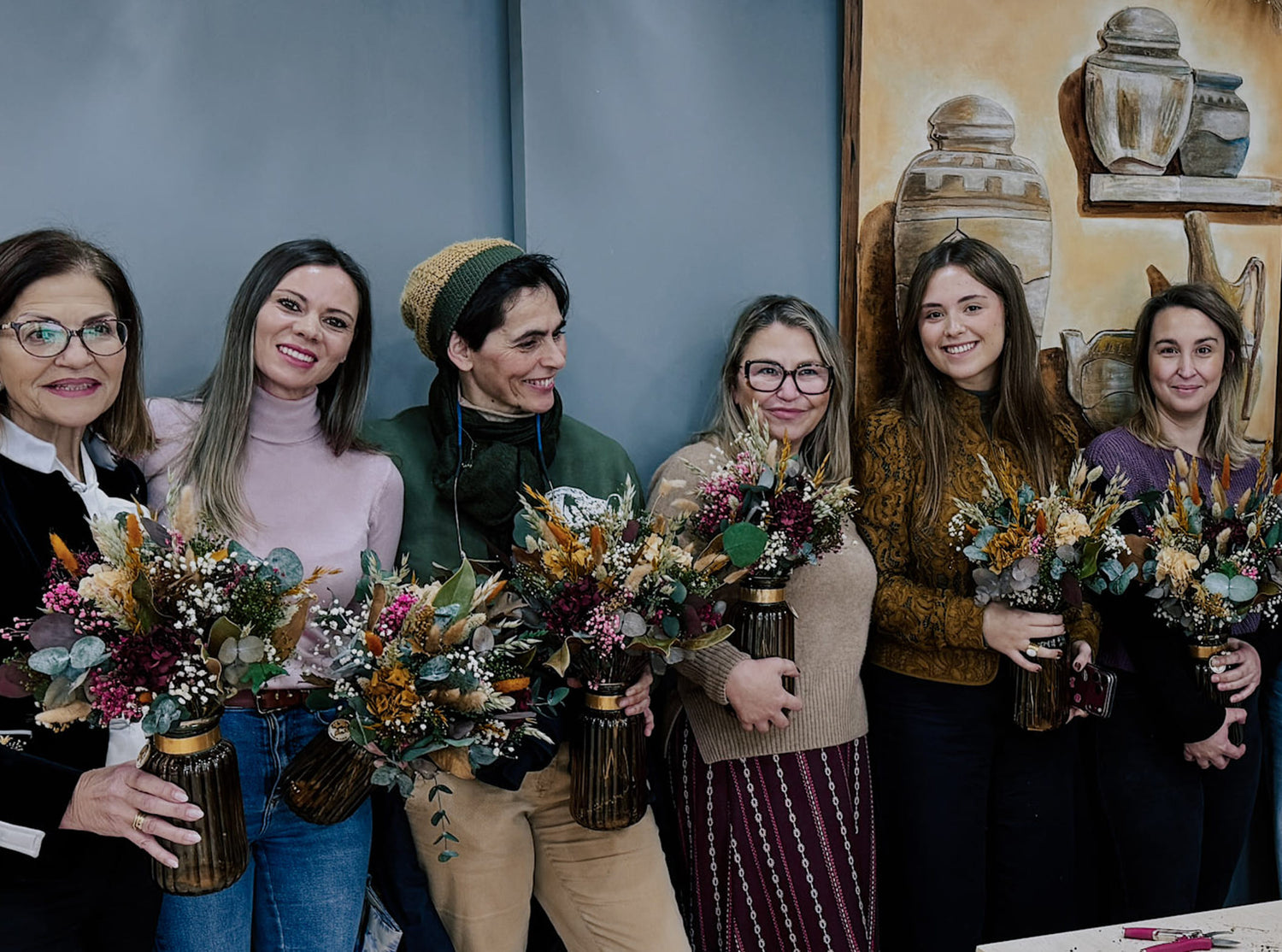 grupo de amigas enseñando el arreglo que han creado en el taller floral