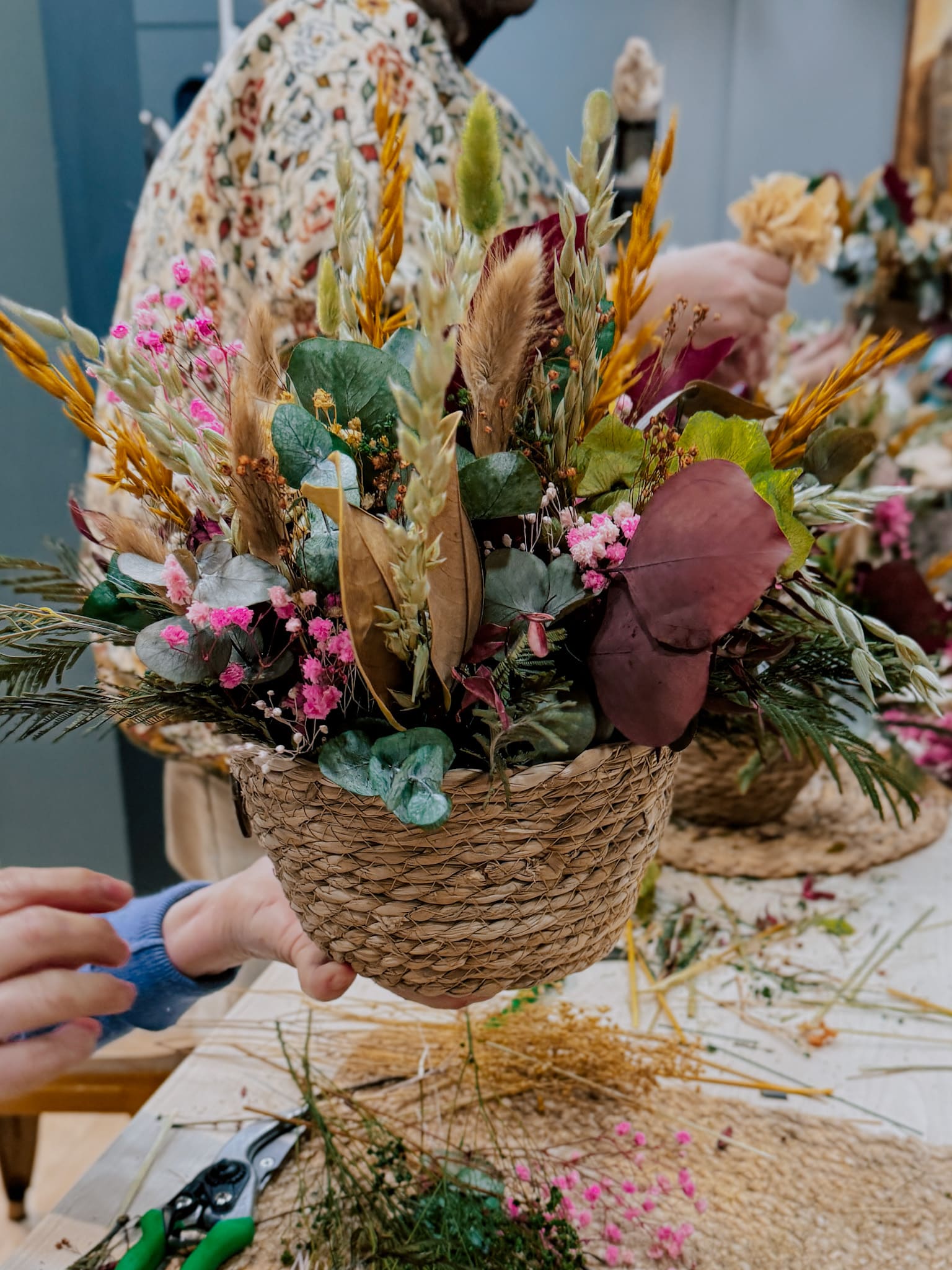 últimos retoques del centro de flores preservadas en base de mimbre