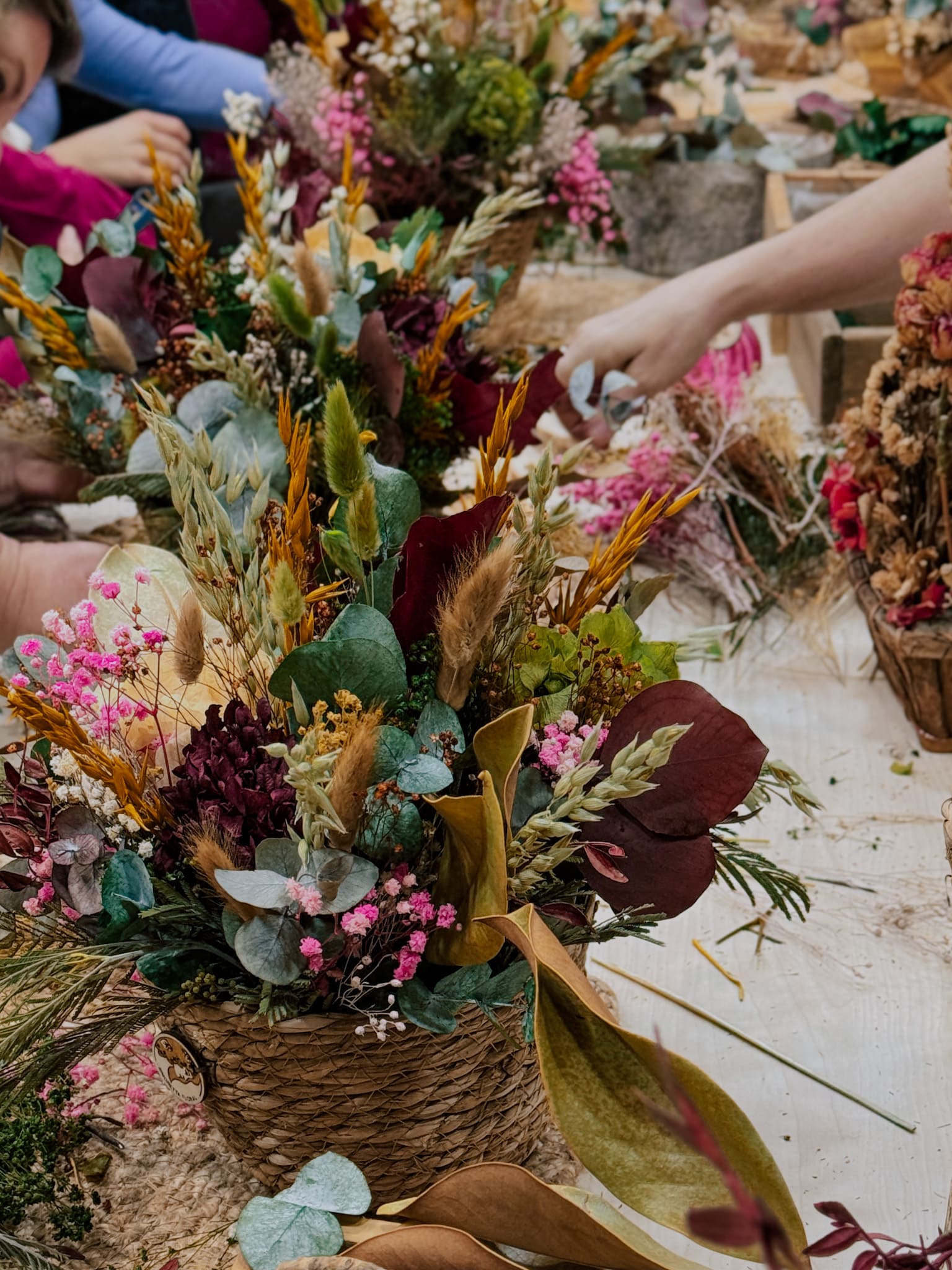 Mesa del taller floral con varios centros de flores preservadas