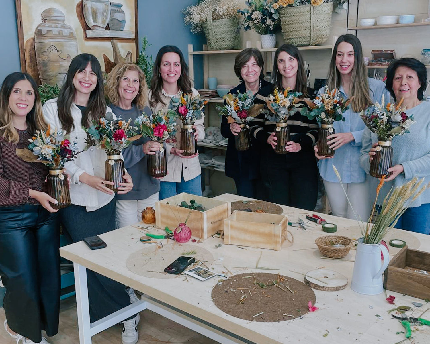 Un grupo de asistentes al taller floral mostrando el resultado de su ramo de flores preservadas